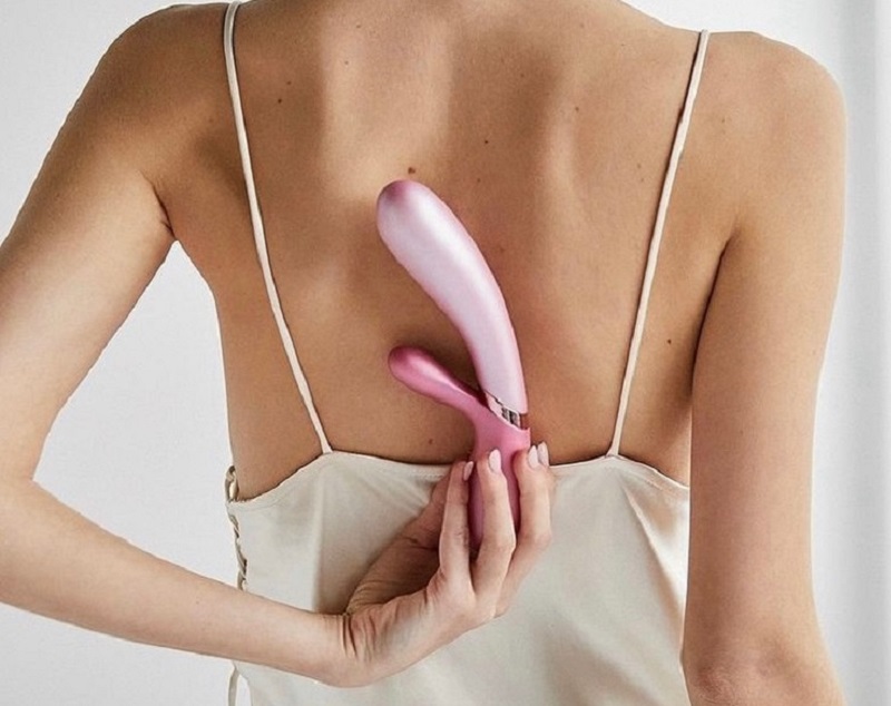 woman holding a vibrator behind her back