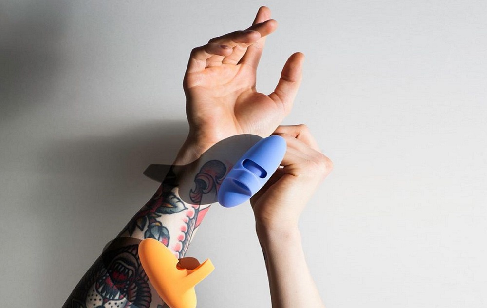 woman holding blue and yellow finger vibrator